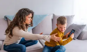 Mutter schimpft mit Sohn, der sein Handy festhält. Ein Beispiel für mögliche ADHS-Erziehungsfehler, wenn Regeln nicht klar sind.