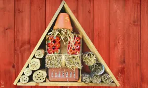 Ein selbstgebautes Insektenhotel für Kinder, gefüllt mit Holzstämmen, Stroh und Ziegeln, bietet Unterschlupf für nützliche Insekten.