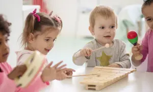 Kinder haben Spaß mit Musik im Kindergarten. Sie spielen Xylophon, Tamburin und Maracas.