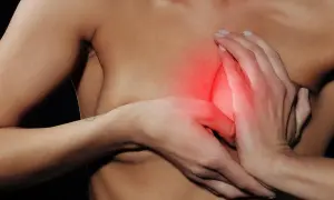 Hände umschließen eine Brust, die rot aufleuchtet. Die Brust fühlt sich weich an, aber das Stillen schmerzt.