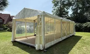 Ein Festzelt im Garten, bereit für eine Einschulungsfeier. Transparente Seitenwände lassen viel Licht herein.