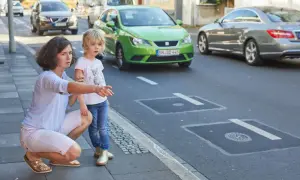 Frau erklärt Kind Verkehrsregeln am Zebrastreifen. Verkehrserziehung im Kindergarten ist wichtig.