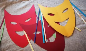 Bunte Karneval Maske Vorlagen liegen auf Stoff. Rot, dunkelrot und gelb. Bänder in verschiedenen Farben stecken an den Masken.