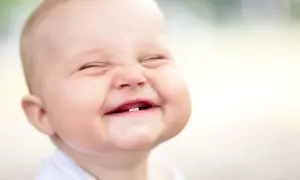 Ein Baby lacht herzhaft, die Augen geschlossen, die Wangen gerötet. Ab wann Babys laut lachen, ist oft eine Überraschung!