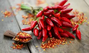 Ein Bund scharfer Chilis und Chiliflocken auf Holz. Perfekt, um jedes Gericht zu würzen und den Geschmack zu stillen.