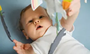Ein neugieriges Baby, 15 Wochen alt, streckt seine Hand nach einem Spielzeug aus.