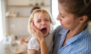Mutter tröstet ihr weinendes Kind, das einen Wutanfall hat.