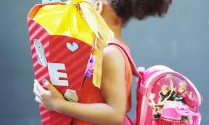Ein Mädchen feiert die Einschulung mit einer bunten Zuckertüte und einem Rucksack mit Frozen-Motiv.