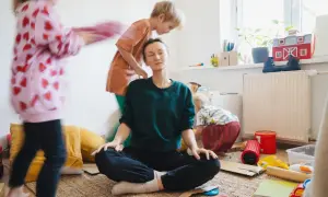 Mama Burnout? Sie meditiert inmitten des Chaos ihrer Kinder. Ein Moment der Ruhe, um Kraft zu tanken.