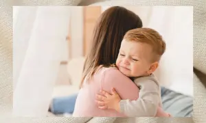Ein weinendes Baby klammert sich an seine Mutter. Es ist ein echter Klettverschluss-Baby, das Trost sucht.