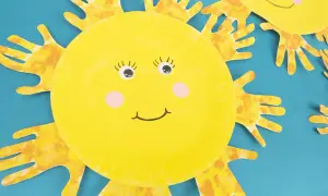 Süße Sonnen-Bastelarbeit von Kindern: Gelbe Pappteller-Sonnen mit Handabdruck-Strahlen und fröhlichen Gesichtern.