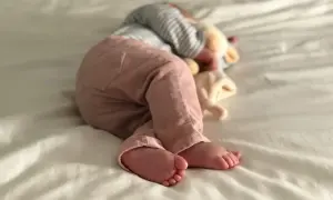 Ein Baby schläft auf einer weißen Decke, die Füße nach vorne gestreckt. Es ist ein Zeichen für einen Wachstumsschub, wenn Babys so tief und fest schlafen.