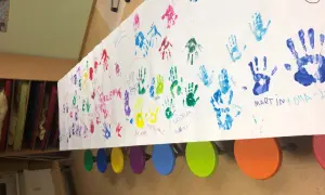 Bunte Handabdrücke von Kindern und Großeltern auf einem langen Papier. Ein Gruß zum Oma Opa Tag.