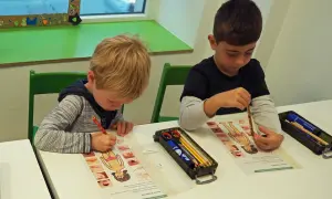 Zwei Jungen lernen in der vorschule kita etwas über den menschlichen Körper. Sie malen und beschriften Arbeitsblätter.