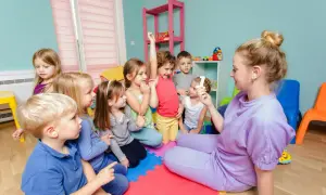 Lehrerin zeigt Kindern im Kindergarten eine Zahl. Alle Kinder sind aufmerksam, ein Zeichen für gelebte Inklusion.