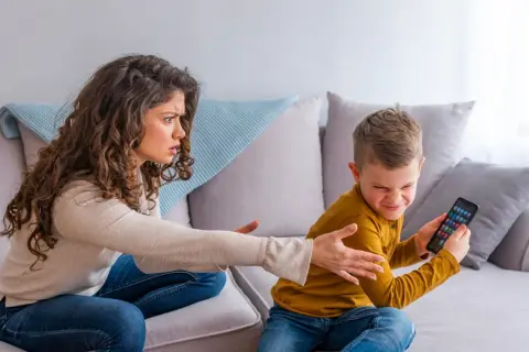 Mutter schimpft mit Sohn, der sein Handy festhält. Ein Beispiel für mögliche ADHS-Erziehungsfehler, wenn Regeln nicht klar sind.