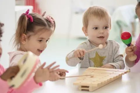 Kinder haben Spaß mit Musik im Kindergarten. Sie spielen Xylophon, Tamburin und Maracas.
