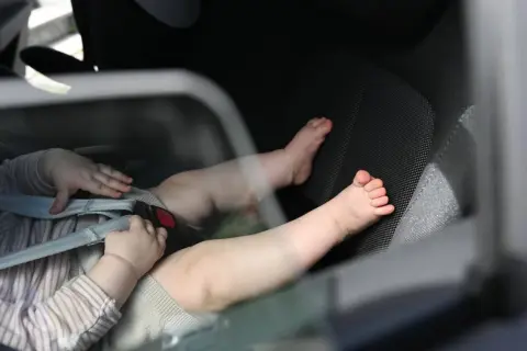 Babyfüße im Kindersitz. Ein trauriges Bild, das an das "forgotten baby syndrome" erinnert, wenn Kinder versehentlich im Auto zurückgelassen werden.