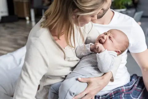 Eltern trösten ihr weinendes Baby. Die späte Stunde ist die "Hexenstunde" für das kleine Kind.
