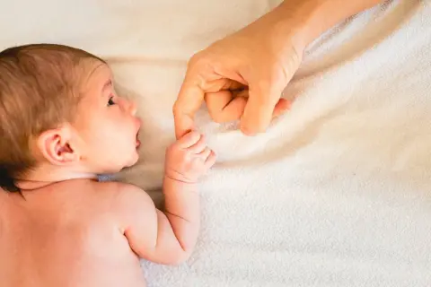 Neugeborenes Baby greift nach dem Finger der Mutter. Ab wann atmen Babys durch den Mund? Diese Frage beschäftigt viele Eltern.