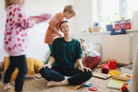 Mama Burnout? Sie meditiert inmitten des Chaos ihrer Kinder. Ein Moment der Ruhe, um Kraft zu tanken.