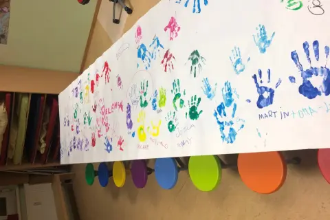 Bunte Handabdrücke von Kindern und Großeltern auf einem langen Papier. Ein Gruß zum Oma Opa Tag.