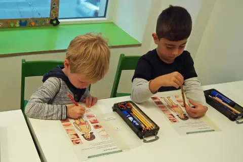Zwei Jungen lernen in der vorschule kita etwas über den menschlichen Körper. Sie malen und beschriften Arbeitsblätter.