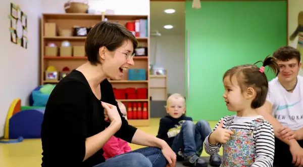 Lehrerin erklärt, ab wann ein Kind "Ich" sagt. Ein kleines Mädchen zeigt auf sich.