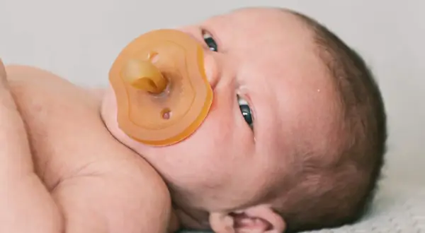 Ein Neugeborenes mit Schnuller. Die Frage "ab wann Schnuller Baby?" beschäftigt viele Eltern.
