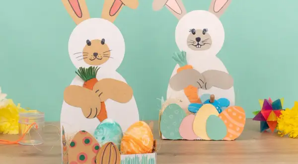 Zwei Bastelhasen mit Karotten und Ostereiern, eine schöne Idee für Ostern im Kindergarten.
