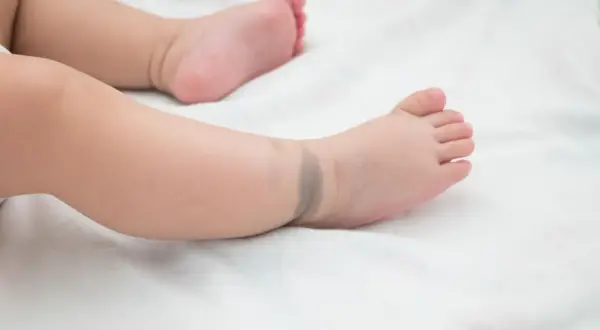 Ein Babyfuß mit einem bläulichen mongolenfleck am Knöchel.