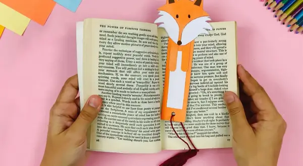 Ein Fuchs-Lesezeichen, gebastelt nach Vorlagen zum Ausdrucken, steckt in einem Buch.