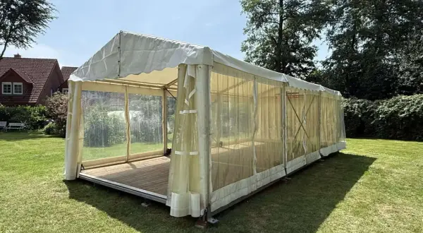 Ein Festzelt im Garten, bereit für eine Einschulungsfeier. Transparente Seitenwände lassen viel Licht herein.