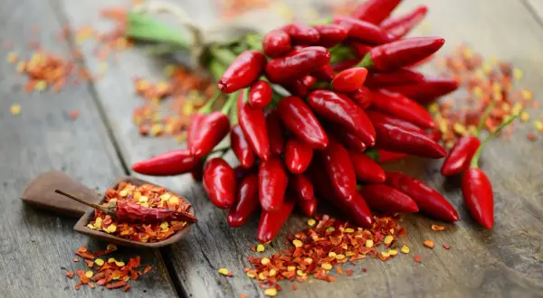 Ein Bund scharfer Chilis und Chiliflocken auf Holz. Perfekt, um jedes Gericht zu würzen und den Geschmack zu stillen.