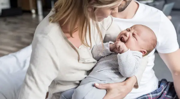 Eltern trösten ihr weinendes Baby. Die späte Stunde ist die "Hexenstunde" für das kleine Kind.