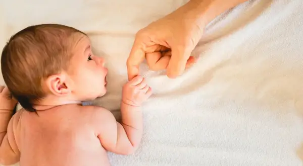 Neugeborenes Baby greift nach dem Finger der Mutter. Ab wann atmen Babys durch den Mund? Diese Frage beschäftigt viele Eltern.