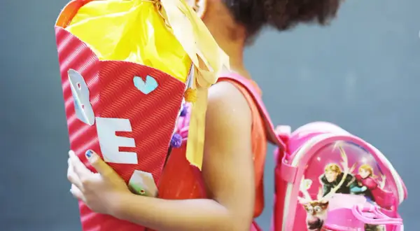 Ein Mädchen feiert die Einschulung mit einer bunten Zuckertüte und einem Rucksack mit Frozen-Motiv.