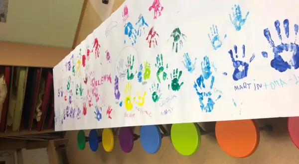 Bunte Handabdrücke von Kindern und Großeltern auf einem langen Papier. Ein Gruß zum Oma Opa Tag.