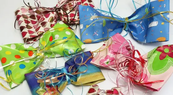 Bunte Schleifen aus Krepppapier basteln: Eine Sammlung von selbstgemachten Geschenkschleifen in verschiedenen Mustern und Farben, bereit zum Verzieren.