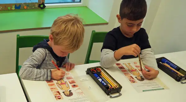 Zwei Jungen lernen in der vorschule kita etwas über den menschlichen Körper. Sie malen und beschriften Arbeitsblätter.