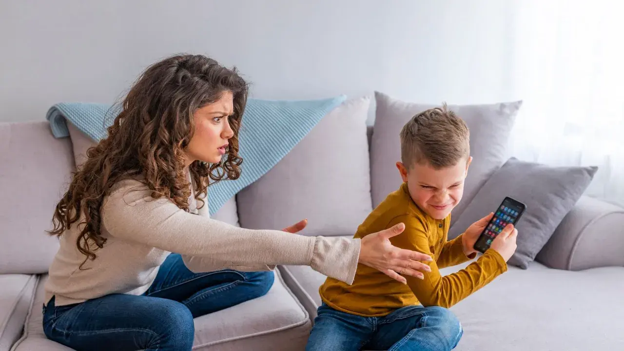 Mutter schimpft mit Sohn, der sein Handy festhält. Ein Beispiel für mögliche ADHS-Erziehungsfehler, wenn Regeln nicht klar sind.