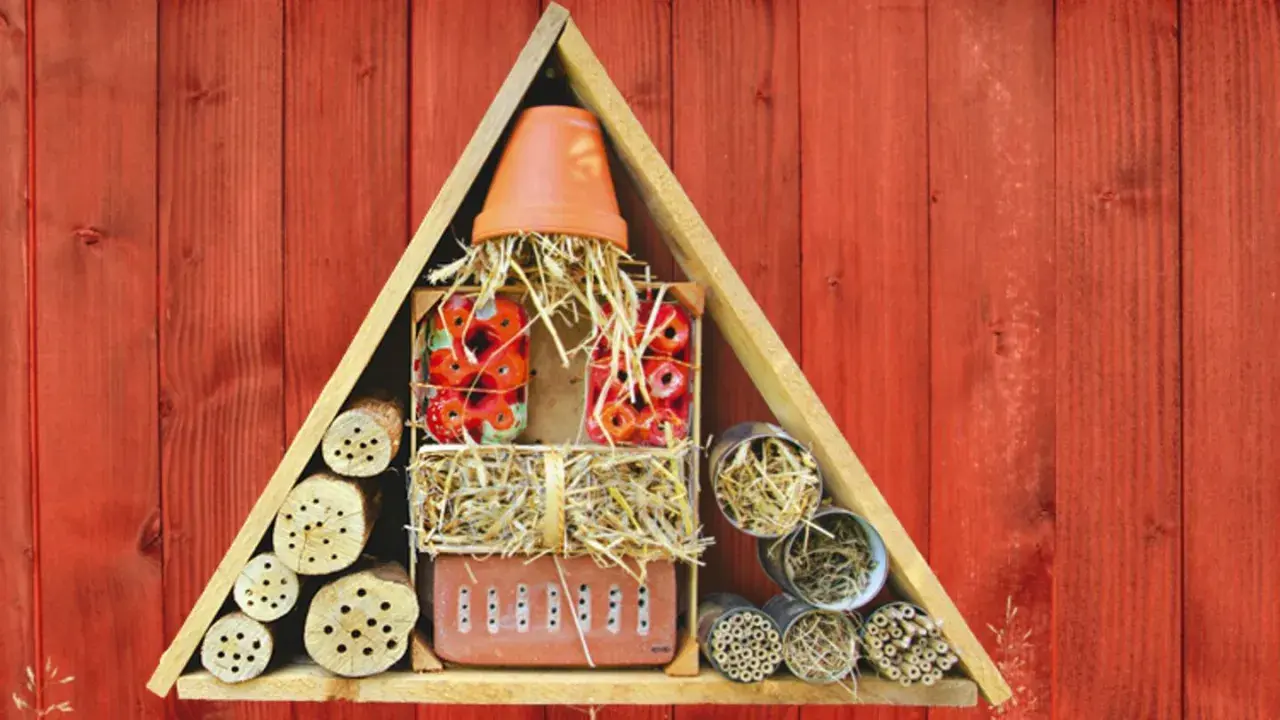 Ein selbstgebautes Insektenhotel für Kinder, gefüllt mit Holzstämmen, Stroh und Ziegeln, bietet Unterschlupf für nützliche Insekten.
