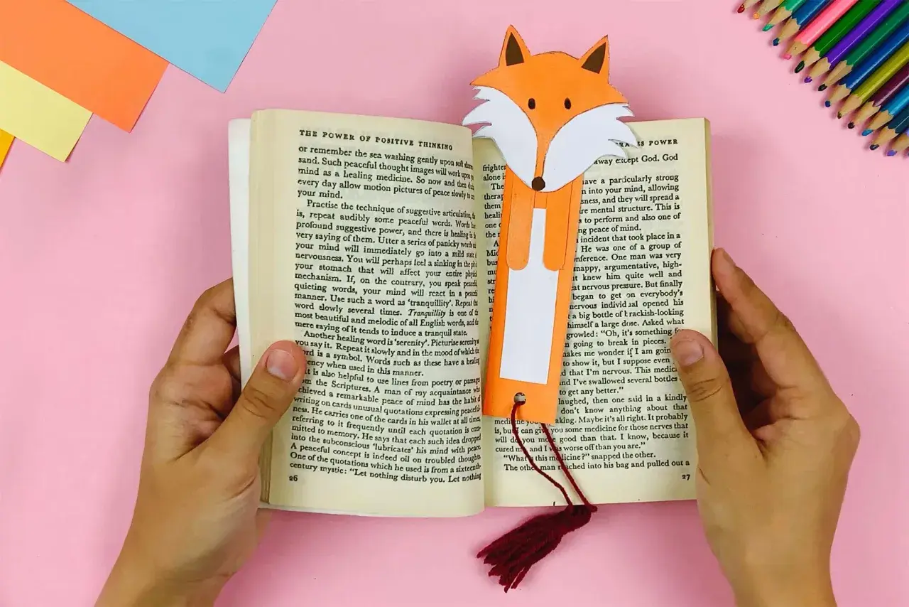 Ein Fuchs-Lesezeichen, gebastelt nach Vorlagen zum Ausdrucken, steckt in einem Buch.