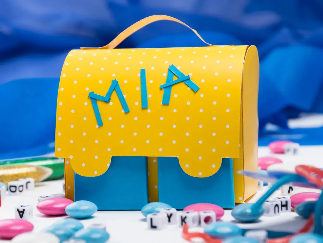 Ein gelber, gepunkteter Schulranzen zum Selberbasteln mit dem Namen "Mia" und blauen Buchstaben.