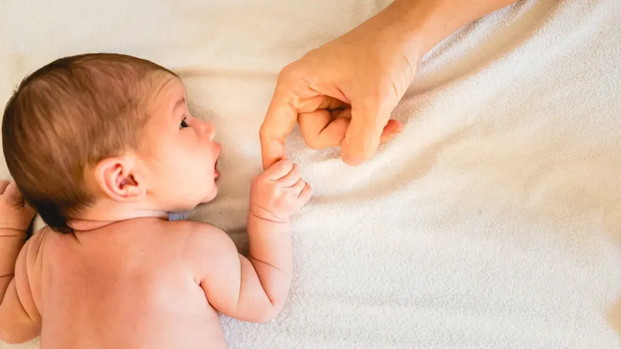 Neugeborenes Baby greift nach dem Finger der Mutter. Ab wann atmen Babys durch den Mund? Diese Frage beschäftigt viele Eltern.