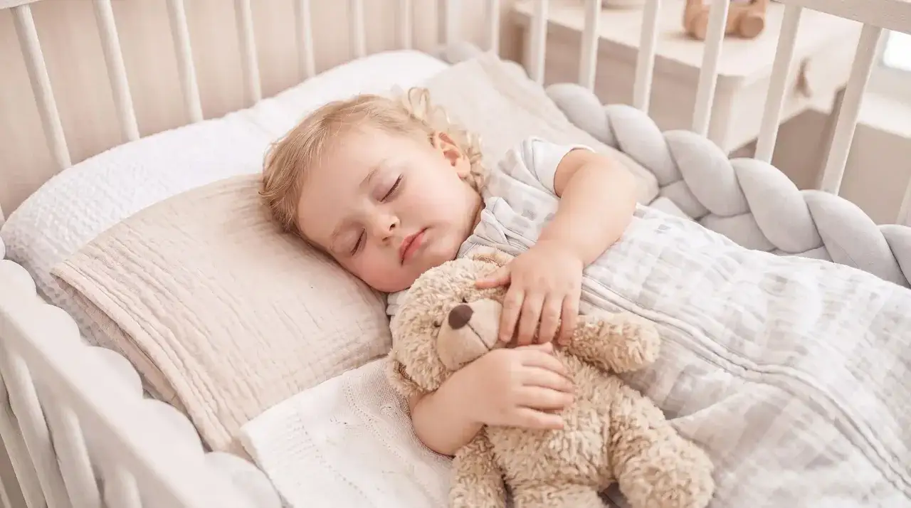 Ein süßes Baby schläft friedlich mit seinem Teddy im Bett. Dieses Baby ist 16 Wochen alt und genießt seinen wohlverdienten Schlaf.