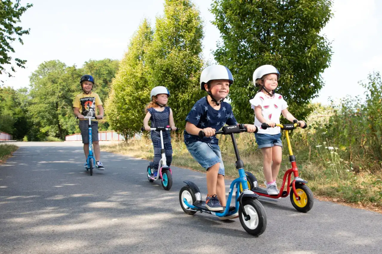 Kinder &uuml;ben auf Rollern im Freien, ein Beispiel f&uuml;r Verkehrserziehung im Kindergarten.