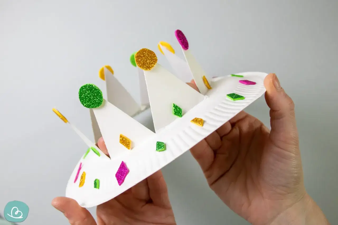 Bastelanleitung: krone selber basteln mit Glitzer-Aufklebern. Eine weiße Papierkrone wird mit bunten Glitzersteinchen verziert.