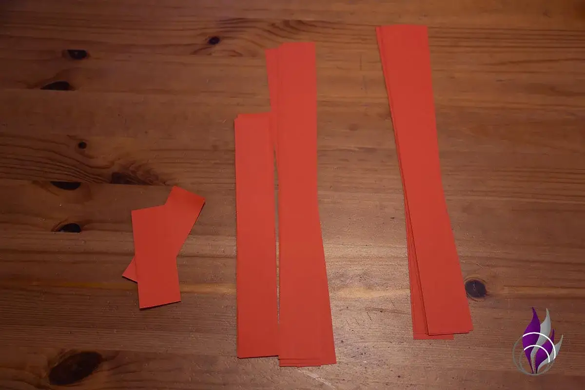 Rote Papierstreifen liegen bereit, um eine Schleife aus Krepppapier zu basteln.