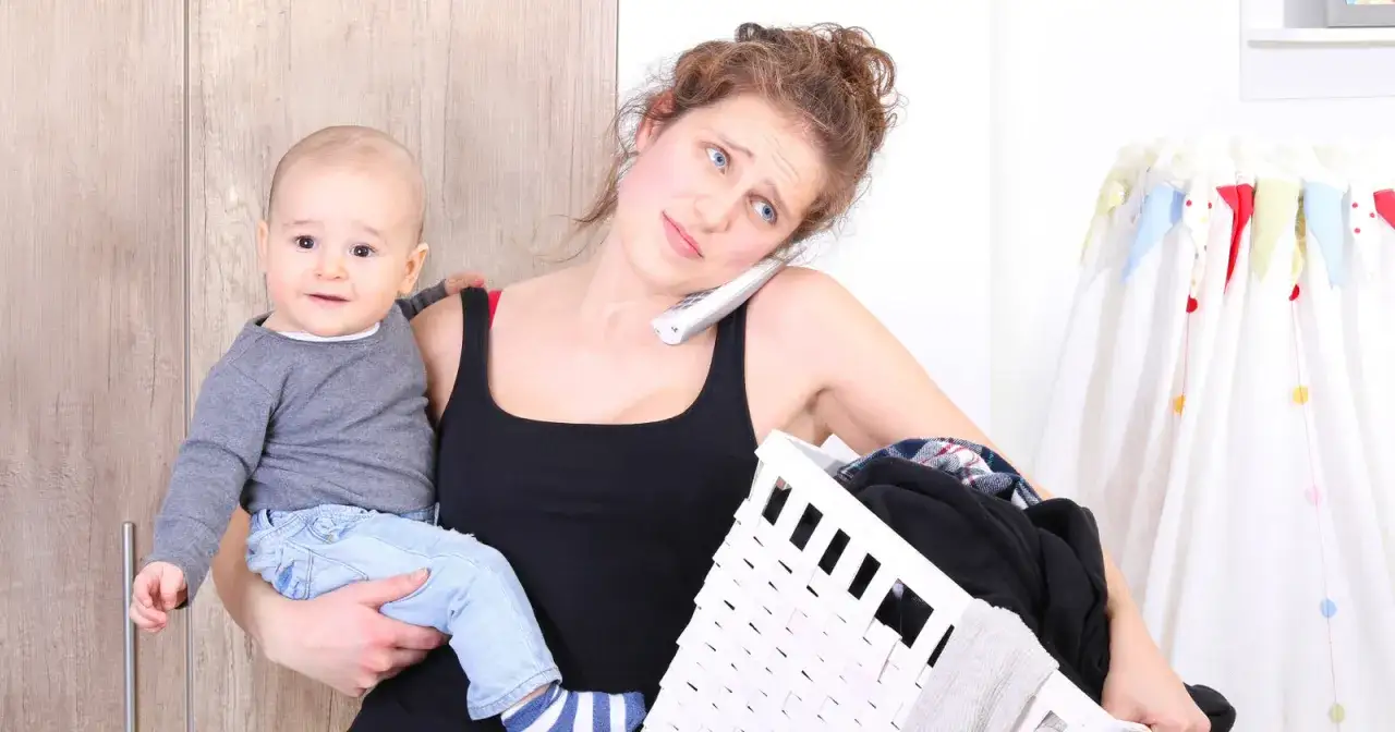 Überforderte mama steht kopf, hält Baby und Wäschekorb, telefoniert.